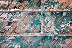 Peeling teal and white paint on wood boards laid diagonally