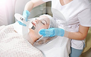 Peeling treatment background. Cosmetologist doing professional ultrasonic face peel for the young woman