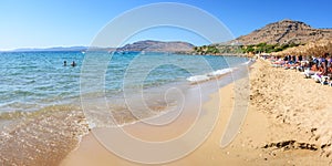 Pefkos beach with holiday-makers, sun beds and umbrellas in village of Pefkos - PANORAMA Rhodes, Greece