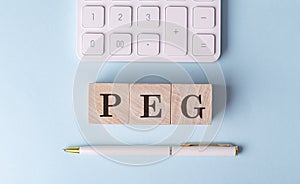 PEG on wooden cubes with pen and calculator, financial concept