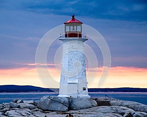 Peggy`s Cove Lighthouse at sunset with storm clouds