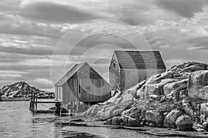 Peggy`s Cove, Nova Scotia fishing sheds with rocky cliffs iin black and white.