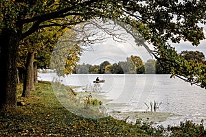 Peizaz with river and forest. Trees over water. Fisherman in a b