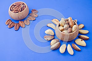 Pekan and brazil nuts on blue background. Healthy food