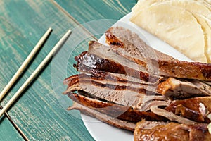 Peking Duck - Chinese roast duck pancakes on wooden green table with chopsticks close up