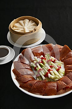 Peking duck with spring onion, cucumber and sweet bean sauce with pancakes, Beijing roast duck on black background