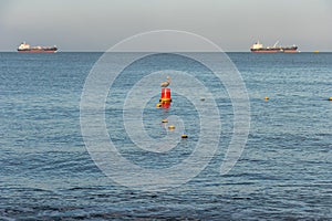 Pelican resting on red buoy in calm sea