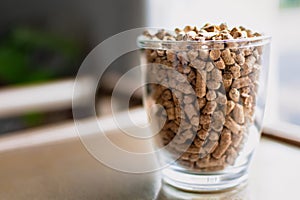 Pellet for stove or boiler in a glass, compressed wood granule photo