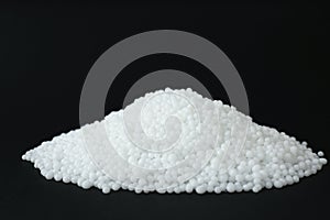 Pellets of ammonium nitrate on black background, space for text. Mineral fertilizer photo