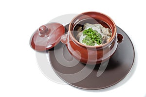 Pelmeni and mushrooms in a clay pot