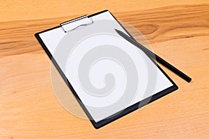 Pen on blank white document sheet on wood clipboard on white wood table top view space