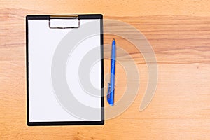 Pen on blank white document sheet on wood clipboard on white wood table top view space
