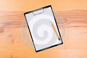 Pen on blank white document sheet on wood clipboard on white wood table top view space