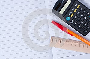 Pen, calculator and ruler on notebook