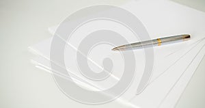 A pen on clean white blank sheets of paper on the table