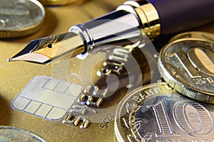 Pen and coins on a credit card close-up
