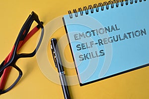Pen, eyeglasses and notebook written with text EMOTIONAL SELF-REGULATIONS SKILLS photo