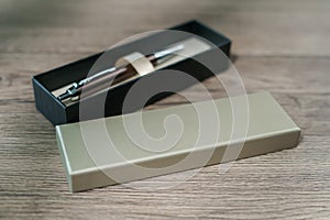 A pen in a gift box on brown wood table background