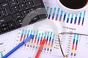 Pen, glasses, computer keyboard and cup of coffee on financial graph, business concept