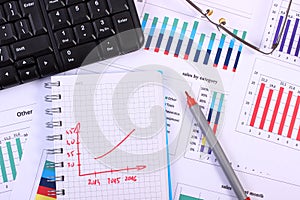 Pen, glasses and computer keyboard on financial graph, business concept