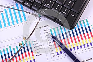 Pen, glasses and computer keyboard on financial graph, business concept