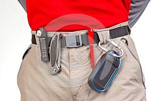 Pen, knife and flashlight with clips on the waistband of trekking pants. EDC items