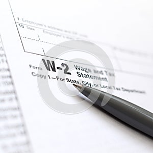 The pen lies on the tax form W-2 Wage and Tax Statement. The tim