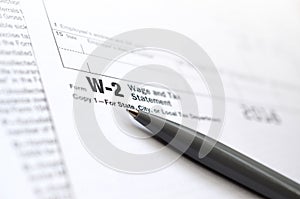 The pen lies on the tax form W-2 Wage and Tax Statement. The tim