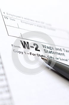 The pen lies on the tax form W-2 Wage and Tax Statement. The tim