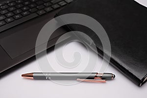 Pen, little black notebook, and laptop computer