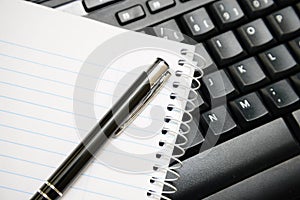 Pen and notebook on computer keyboard