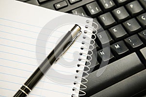 Pen and notebook on computer keyboard
