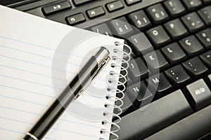 Pen and notebook on computer keyboard