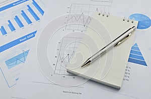 Pen and notebook on financial chart and graph