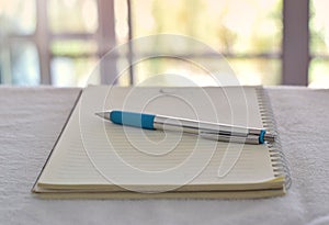 pen in notebook on office desk with blurry background