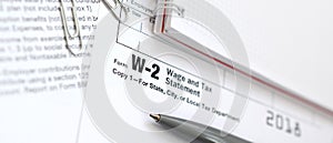 The pen and notebook on the tax form W-2 Wage and Tax Statement.