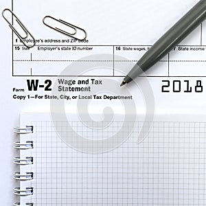 The pen and notebook on the tax form W-2 Wage and Tax Statement.