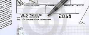 The pen and notebook on the tax form W-2 Wage and Tax Statement.