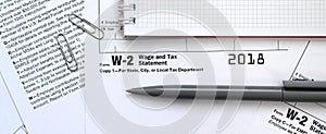 The pen and notebook on the tax form W-2 Wage and Tax Statement.