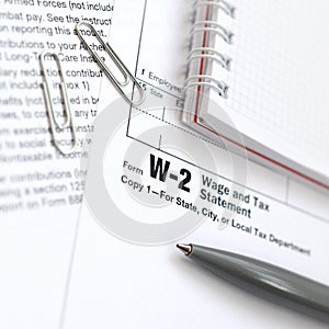 The pen and notebook on the tax form W-2 Wage and Tax Statement.