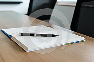 Pen on notepad for agenda kept on table in corporate conference room