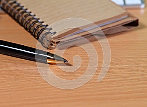 Pen with notepad on wooden table.