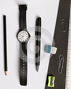Pen, pencil, eraser, pencil sharpener, wristwatch and ruler on a contrasting black and white background