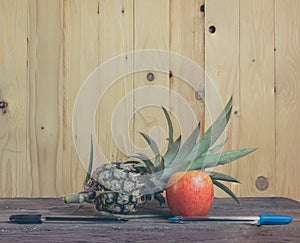 Pen-Pineapple-Apple-Pen on wooden background.