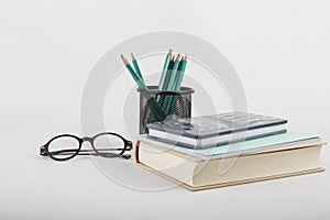 Pen, reading glasses, book and notebook on white background