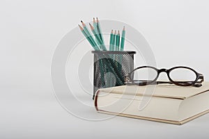 Pen, reading glasses, book and notebook on white background