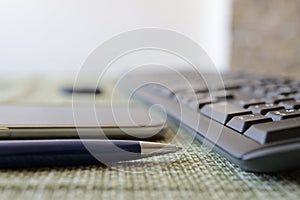 pen, smartphone and keyboard on table close up