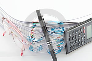 Pen and step pile of paperwork with spectacles and calculator