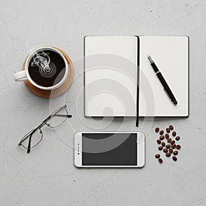 Pen on a textured light gray surface. Cup of steaming coffee on