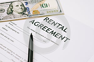 Pen and US Dollar banknotes money on rental agreement form document, ready to sign contract, property or real estate deal between